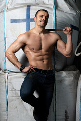 Fototapeta na wymiar Muscular Bodybuilder Flexing Muscles Standing Strong in Warehouse
