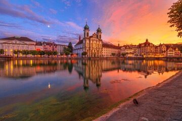 Amazing sunset with colorful clouds in city downtown of Lucerne in Central Switzerland. Jesuitenkirche or Jesuit Church of St. Francis Xavier reflecting on Reuss river of Lucerne's historical city.