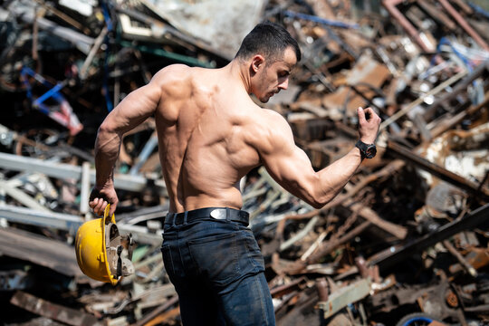 Man Flexing Muscles in Industrial Junk Yard