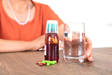 Chinese old lady holding a glass of water is about to take medicine