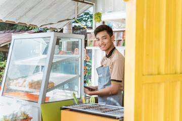 proud young asian man small business owner at his shop made of truck container selling street food