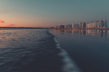 Fototapeta premium Wave to the edge of the beach and reflect the buildings.