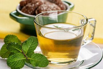 a cup of mint tea with some sweet cookies in the background