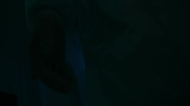 Dark blurred hospital corridor with a silhouette of a man in coverall. Stock footage. Unrecognizable person in protective suit, interior of a horror quest room.