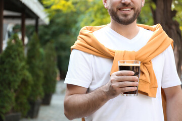 Young man with cold kvass outdoors, closeup. Traditional Russian summer drink