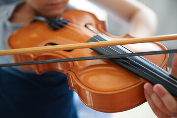 Young woman teaching little boy to play violin indoors, closeup © New Africa