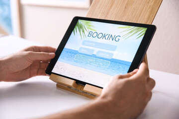 Fototapeta na wymiar Man booking tickets online on tablet at white table, closeup. Travel agency concept