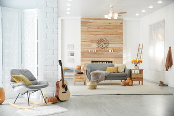 Cozy living room interior with comfortable furniture, guitar and autumn decor
