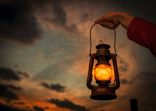 Female's hand holding a lantern with the beautiful sunset in the background