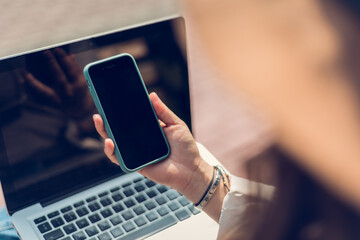 Hand of a woman holding a smart phone outdoors