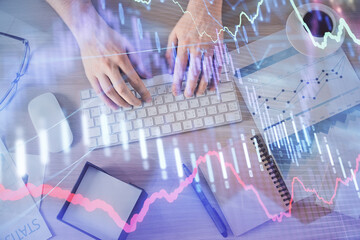 Multi exposure of man's hands typing over computer keyboard and forex graph hologram drawing. Top view. Financial markets concept.