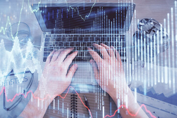 Multi exposure of man's hands typing over computer keyboard and forex graph hologram drawing. Top view. Financial markets concept.