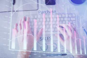 Double exposure of man's hands typing over laptop keyboard and forex chart hologram drawing. Top view. Financial markets concept.