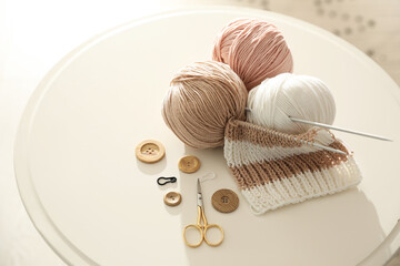 Yarn balls and knitting accessories on white table. Creative hobby - obrazy, fototapety, plakaty