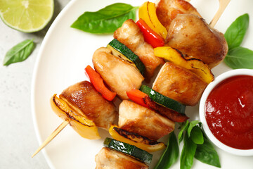 Delicious chicken shish kebabs with vegetables and ketchup on grey table, top view
