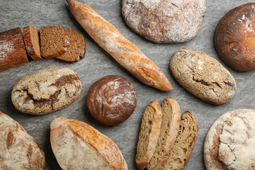 Different kinds of fresh bread on grey table, flat lay
