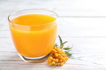 Delicious sea buckthorn juice and fresh berries on white wooden table, closeup. Space for text