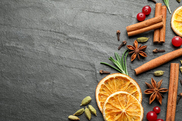 Different mulled wine ingredients on black slate table, flat lay. Space for text