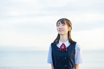 海を背景に、笑顔を見せる女子高生