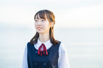 海を背景に、笑顔を見せる女子高生