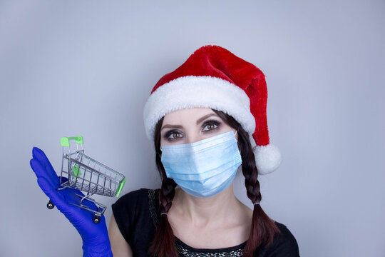 Woman wearing protection face mask against coronavirus. Woman in a mask and Christmas hat and holding shopping cart. Medical mask, Close up shot, Select focus, Prevention from covid19