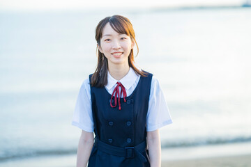 海を背景に、笑顔を見せる女子高生