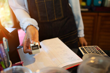 Employees are using hands to calculate expenses from the machine to collect money in the coffee shop.