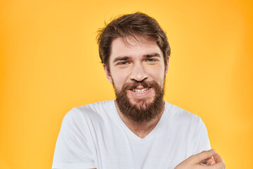 Obraz premium Man with emotional expression white t-shirt close-up studio yellow background