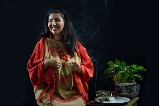 
Mujer latina con cabello negro ojos expresivos y sonriente con hermosa sonrisa, sobre fondo negro, viste ropa &eacute;tnica y mant&oacute;n negro, sanadora y sanadora mexicana