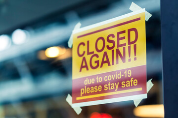 window store glass door entrance handing closed sign shop again from covid-19 spread and lockdown...