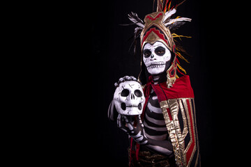 hombre latino , catrin de dios azteca, calavera prehispanica, con saumerio e incienso y fuego, portado penacho de plumas amarillas y rojas en fondo negro, dia de muertos, 1 de noviembre, calaca,