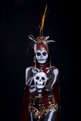 hombre latino , catrin de dios azteca, calavera prehispanica, con saumerio e incienso y fuego, portado penacho de plumas amarillas y rojas en fondo negro, dia de muertos, 1 de noviembre, calaca,