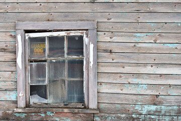 Obraz na płótnie Canvas An image of an old broken window with peeling paint on an abandon building.