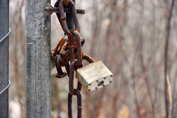 A close up image of a locked padlock on an old rusted chain link gate. 