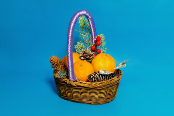 Christmas basket on blue background with lemons, red berries and pine cones.