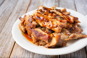 A view of a plate of teriyaki chicken, in a restaurant or kitchen setting.
