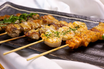 A closeup view of a variety of yakitori meat cuts, in a restaurant or kitchen setting.