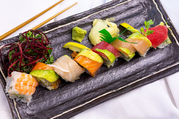 A top down view of a rainbow roll, in a restaurant or kitchen setting.