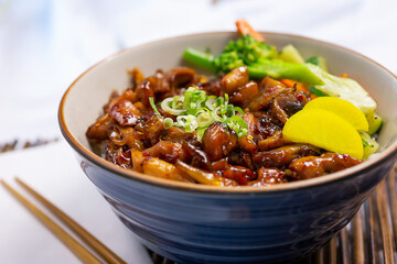 A closeup view of a chicken bowl, in a restaurant or kitchen setting.
