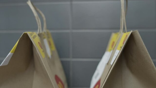 Slider shot of fast food restaurant to-go bags awaiting delivery driver pickup