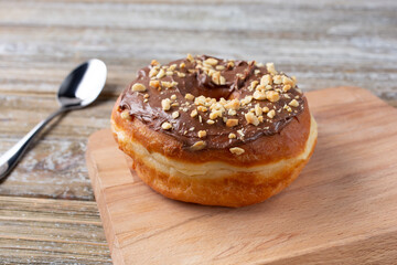 A view of a chocolate glazed donut, with peanut toppings, in a restaurant or kitchen setting.