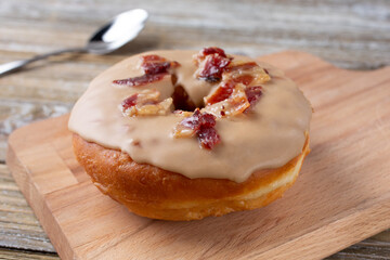 A closeup view of a maple bacon donut, in a restaurant or kitchen setting.