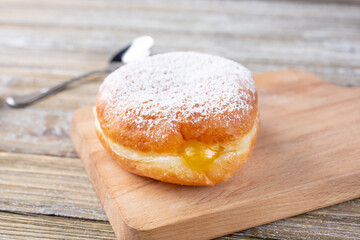 A view of a lemon filled donut, with powdered sugar topping, in a restaurant or kitchen setting.