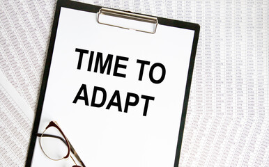 On the letter tablet is the text of TIME TO ADAPT, next to glasses and reports.