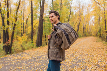 Tall handsome man with a bag on the autumn alley