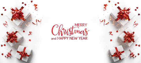 Merry Christmas and Happy New Year text on white background with gift boxes, ribbons, red decoration, fir branches, bokeh, sparkles and confetti. Xmas greeting card, bokeh, light. Top view, banner