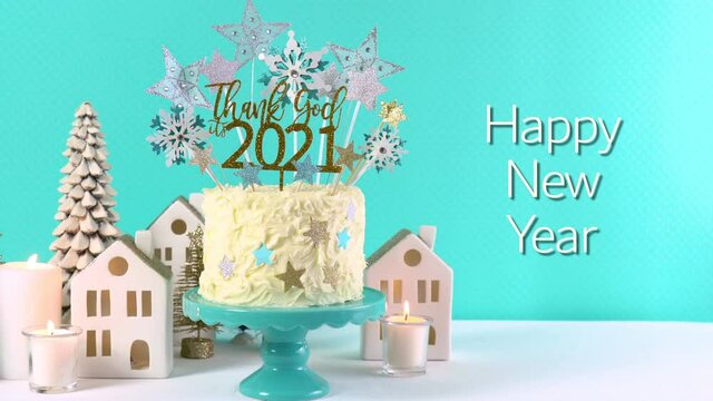 Happy New Year's Eve celebration cake on cake stand in blue white and gold theme decorated with stars and humorous, Thank God It's 2021, cake topper decoration, with animated text.