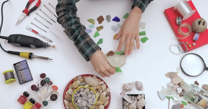Top view on workspace table at craft workshop with tools and materials. Artist working with colourful sea glass at workshop