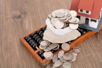 On a traditional Chinese abacus is a bag of dollar coins and a small house model