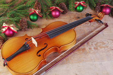 Fototapeta na wymiar Violin and bow, fir branch and Christmas decorations on a wooden background.